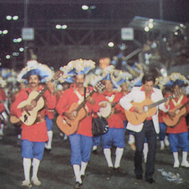 desfile de carnaval, vários homens trajados a rigor, calças, meias e chapéu Sombrero