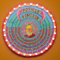 A paz de Paes Loureiro, Pintura, 2019 Letreiro circular onde se lê: “Poemas visuais. A paz de Paes Loureiro. Monarca de monarcas, grão senhor do rio dos encantados, comandante investido no poema. Tu que és sempre um salto no abismo da paixão de ser, seras um Deus ou modelagem humana de um desejo? Tu que aos homens te assemelhas…”. As letras apresentam …