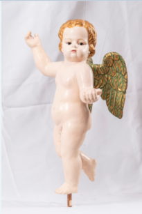 Anjo branco, cachos dourados, asas dourado cobreado. Figura angelical apoiada em um dos pés, braço esquerdo a frente em sinal de cumprimento, braço direito levantada para cima.