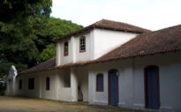 Fotografia do museu físico, bem imóvel de 2 andares, telhado de telhas provavelmente de argila, árvores ao segundo plano