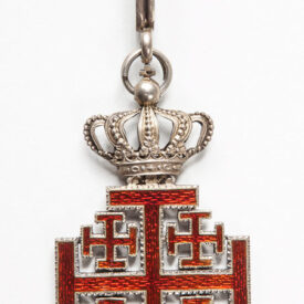 Pingente de colar com coroa ao topo, junto a símbolos em vermelho em formato de x em pé