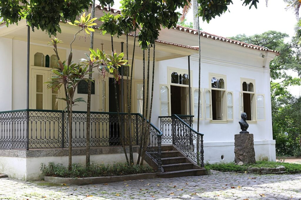 Casa em estilo neoclássico, com gradil de ferro e busto de bronze do patrono.