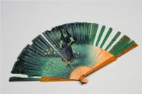 Vinte e seis lâminas de madeira e duas nas extremidades em âmbar, unidas na extremidade inferior por alça em metal dourado. Na parte superior das lâminas de madeira, revestimento em tecido. Decoração floral e figura feminina na parte de tecido e madeira, com friso dourado na parte inferior e frisos azul claro e dourado na parte superior